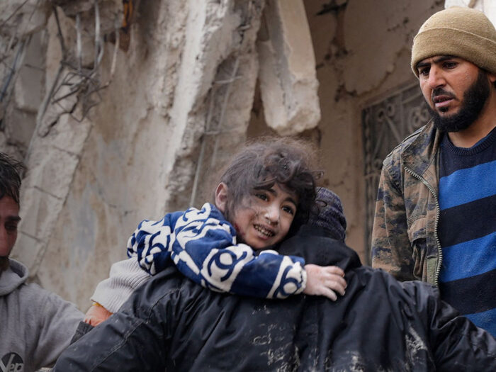 Residents retrieve a small child from the rubble of a collapsed building in Syria after earthquake