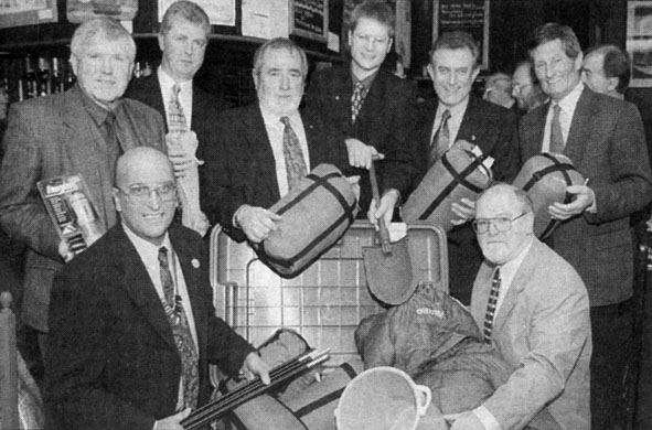Black and white photo of men around a box containing tents and other aid items