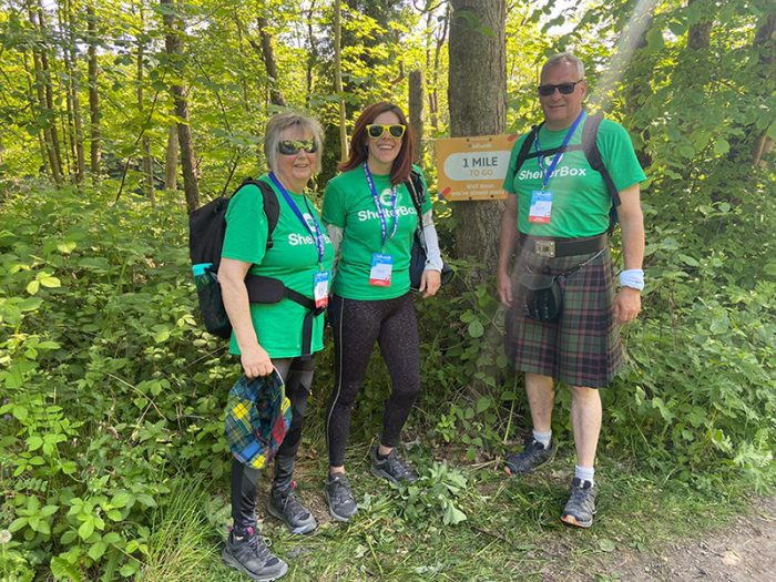 Three people wearing ShelterBox tshirts in a wood