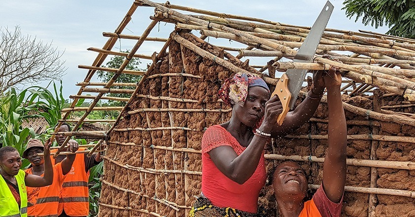 Une femme sciant du bois sur le toit d'un nouvel abri au Mozambique